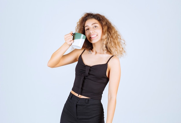 Blondie girl holding a coffee cup as a morning routine. 