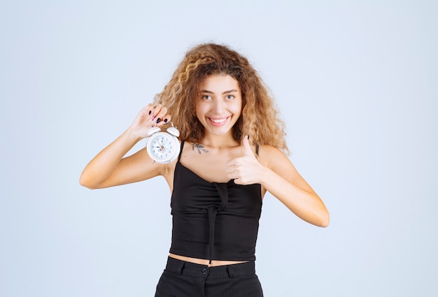 Blondie girl holding and promoting an alarm clock.