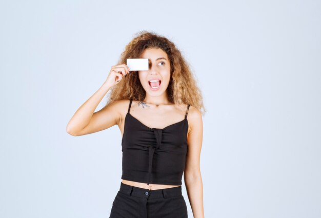 Ragazza bionda che mette il biglietto da visita al suo occhio.