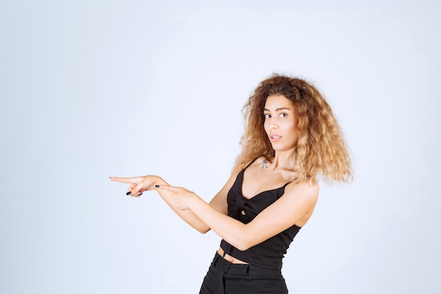 Foto gratuita ragazza bionda con i capelli ricci che puntano a sinistra.