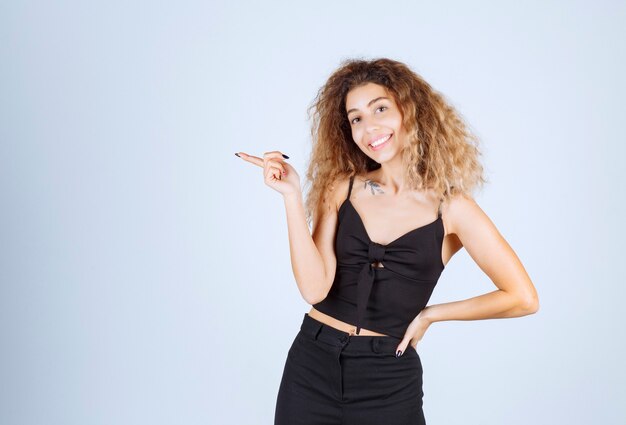 Blondie girl with curly hairs pointing to the left. 