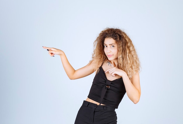 Blondie girl with curly hairs pointing to the left. 