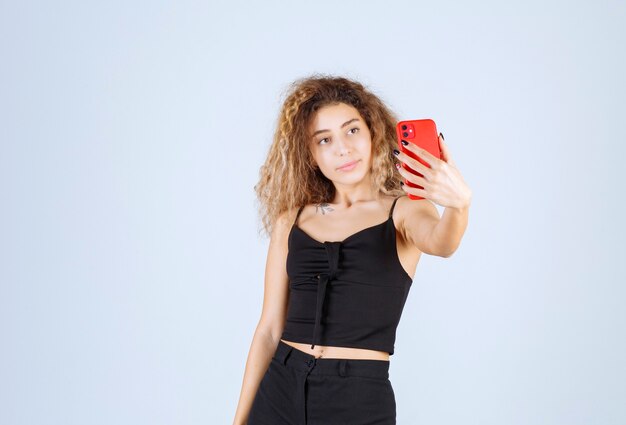 Ragazza bionda con i capelli ricci prendendo il suo selfie.