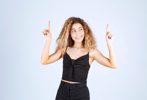 Blondie woman raising her hand up and pointing something above with emotions.