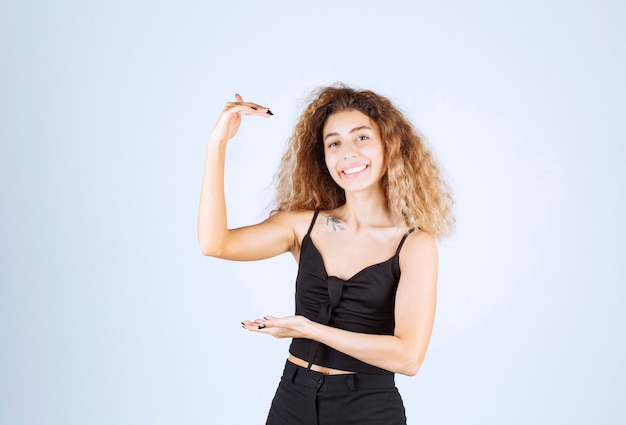 Blondie woman showing the size of an object.