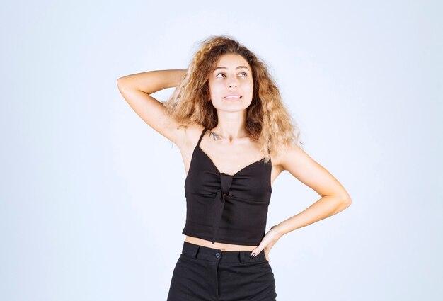 Blondie woman with curly hairs looks confused and lost.