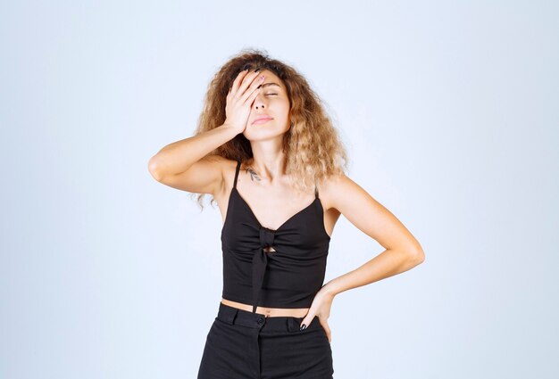 Blondie woman with curly hairs looks sleepy and exhausted.