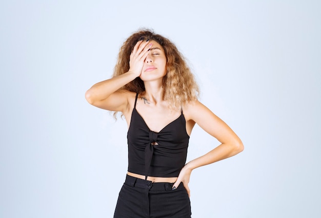 Blondie woman with curly hairs looks sleepy and exhausted.