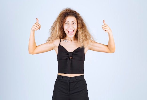 Foto gratuita donna bionda con i capelli ricci che mostrano un buon segno con la mano.