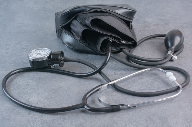 Blood pressure meter and stethoscope on marble table.