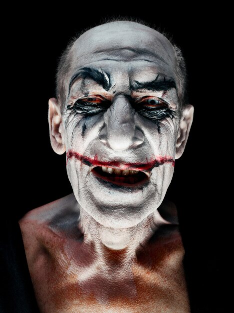 Bloody Halloween theme: The crazy smiling maniak face on dark studio