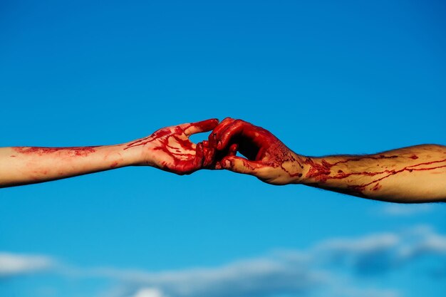 Bloody zombie hands with red blood on blue sky