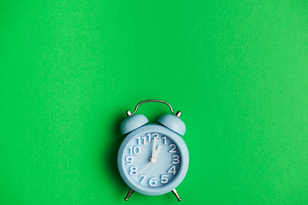 Blue alarm clock against green background