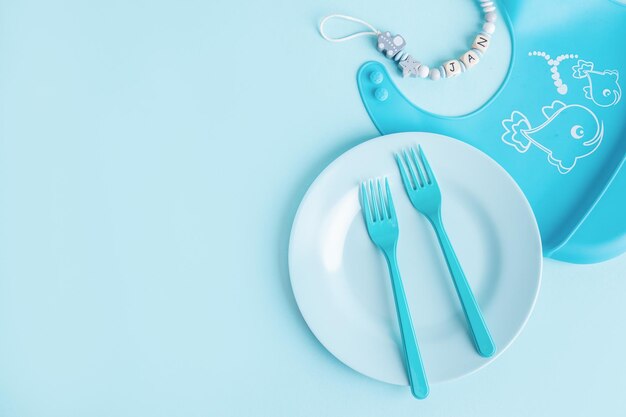 Синяя детская тарелка со столовыми приборами на столе