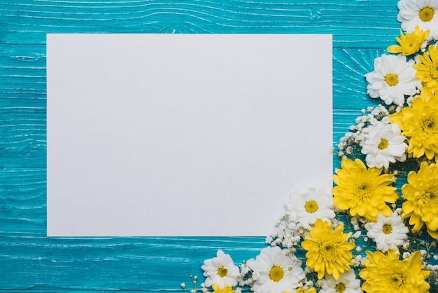 Blue background with piece of paper and decorative flowers