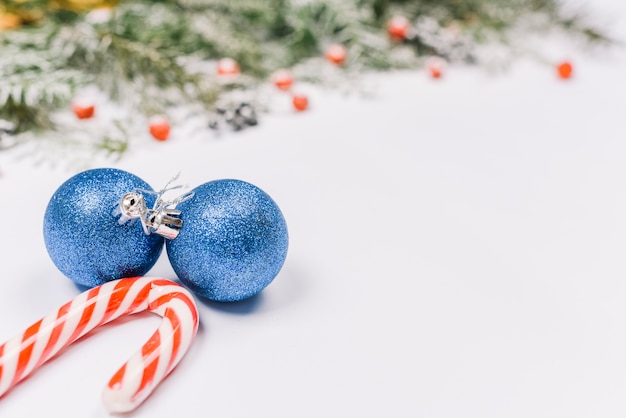 Free photo blue baubles with candy cane near fir branches