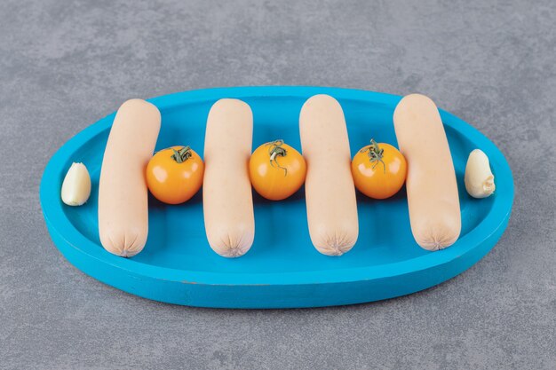 A blue board of boiled sliced sausage with cherry yellow tomato 