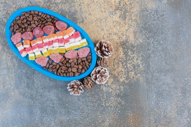 A blue board full of different fruit jelly candies with pinecones. High quality photo