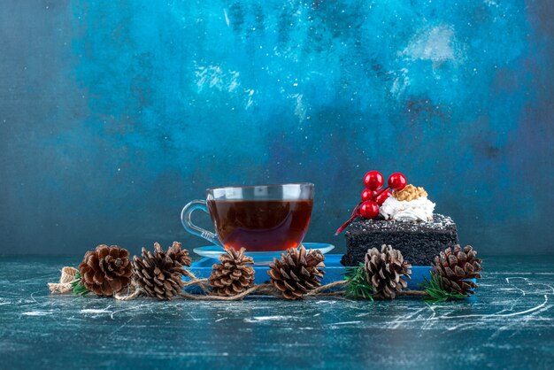 A blue board with a piece of chocolate cake and a cup of tea. High quality photo