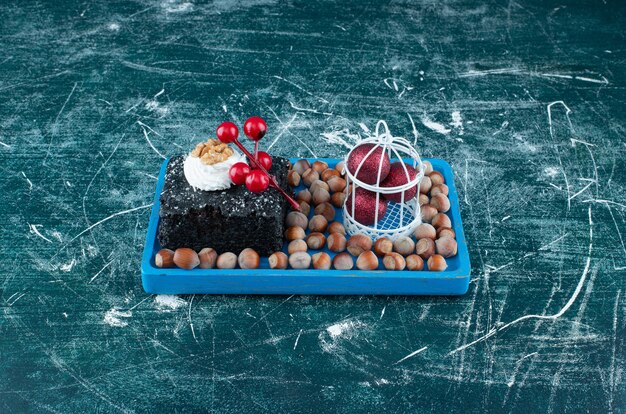 A blue board with a piece of chocolate cake and macadamia nuts. High quality photo