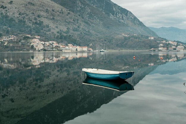 Blue boat in Adriatic Sea gulf with mountains in Montenegro Kotor