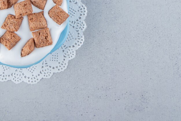 Blue bowl of chocolate pads cornflakes with cream foam. High quality photo