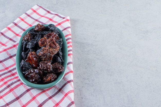 Blue bowl of delicious dried dates on stone background.