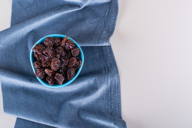 Blue bowl of dried organic plums placed on white background. High quality photo