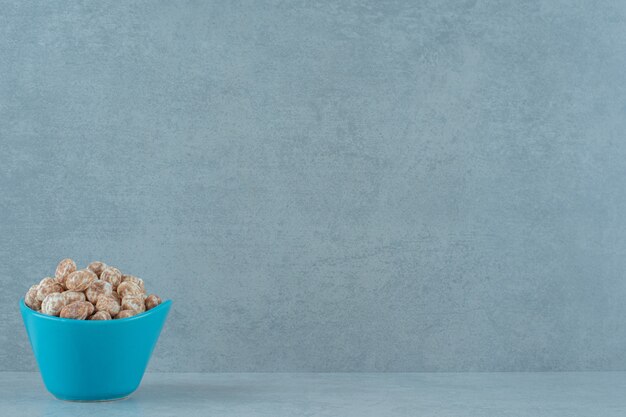 A blue bowl full of sweet delicious gingerbread on white surface