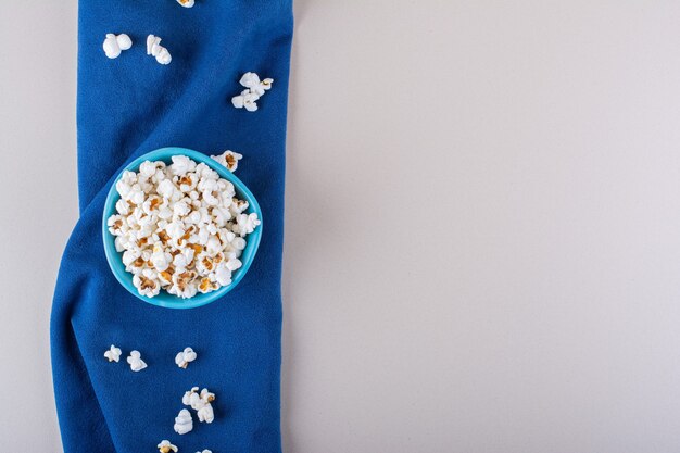 Blue bowl of salted popcorn for movie night on white background. High quality photo