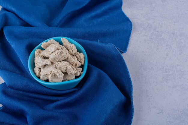 Blue bowl of tasty sunflower halva on stone table. 