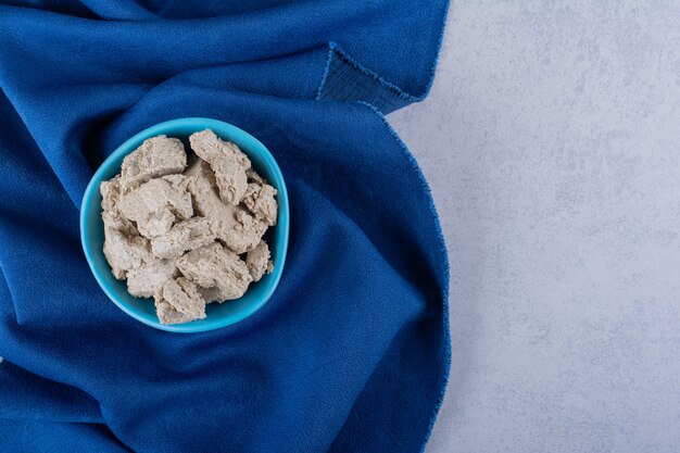 Blue bowl of tasty sunflower halva on stone.