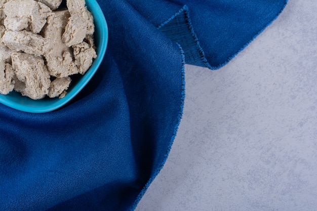 Blue bowl of tasty sunflower halva on stone.