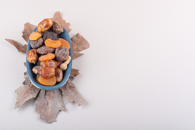 Blue bowl of various organic nuts and fruits on white background. High quality photo