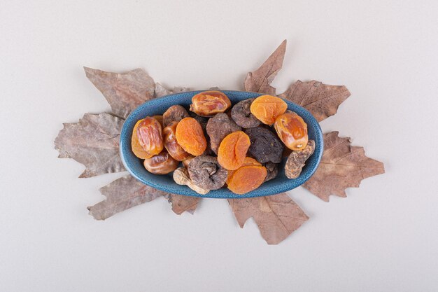 Blue bowl of various organic nuts and fruits on white background. High quality photo