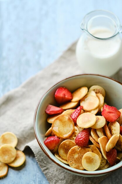 Blue Bowl with cereal tiny pancake with strawberries and maple syrup on a marble board Trendy food conceptxD