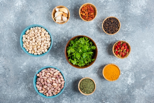 Free photo blue bowls of raw beans and spices on marble background.