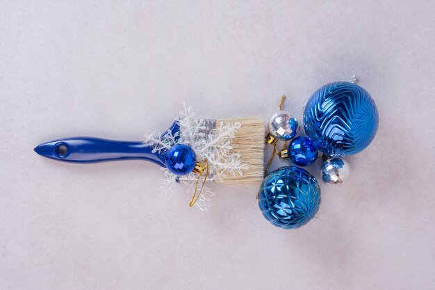 Blue brush with Christmas balls on white surface