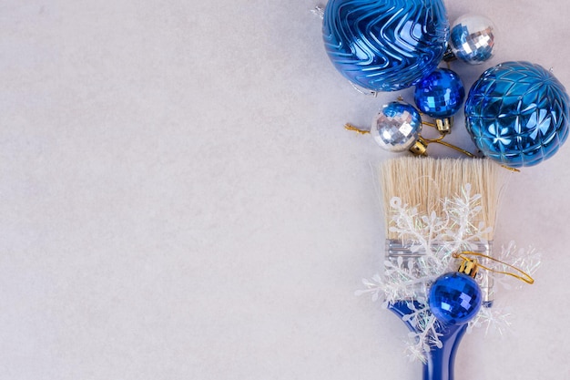 白いテーブルの上のクリスマスボールと青いブラシ。