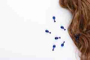 Free photo blue capsules with vitamins for hair lie on brown hair curls