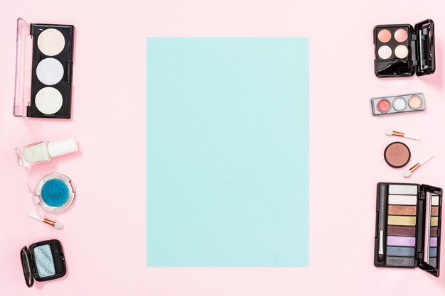 Blue card with copy space for writing the text with makeup cosmetic products on pink background