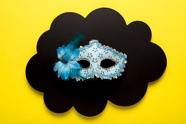 Blue carnival mask on black paper cloud