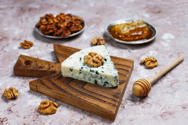 Голубой сыр на деревянной разделочной доске с медом и грецкими орехами