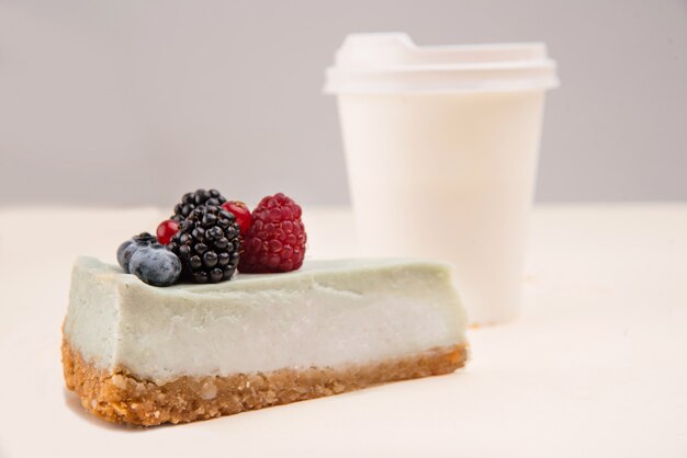 Blue cheesecake near paper cup isolated