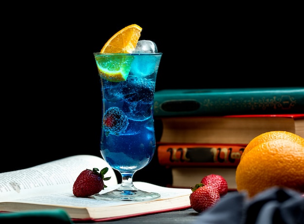 Blue cocktail with blackberry, orange slice, strawberry and ice