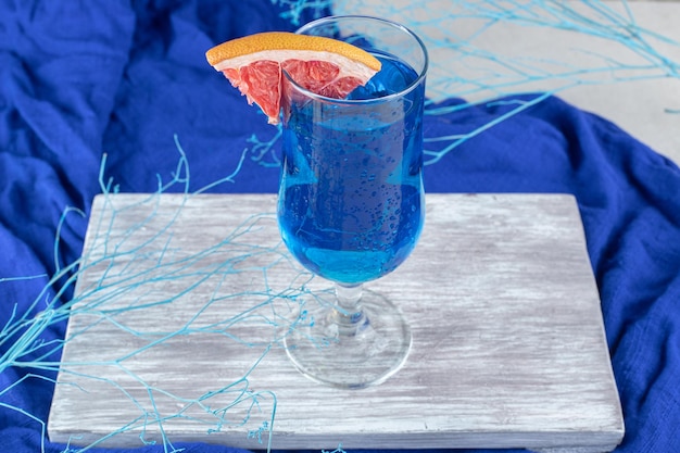 Бесплатное фото Синий коктейль с ломтиком грейпфрута на деревянной доске