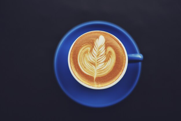 Blue coffee cup with an ear drawn in the foam