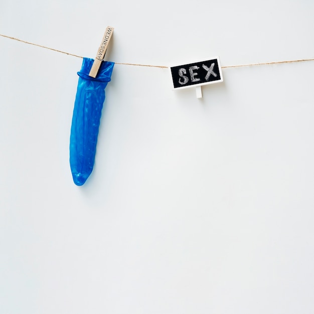 Blue condom on clothesline with white background