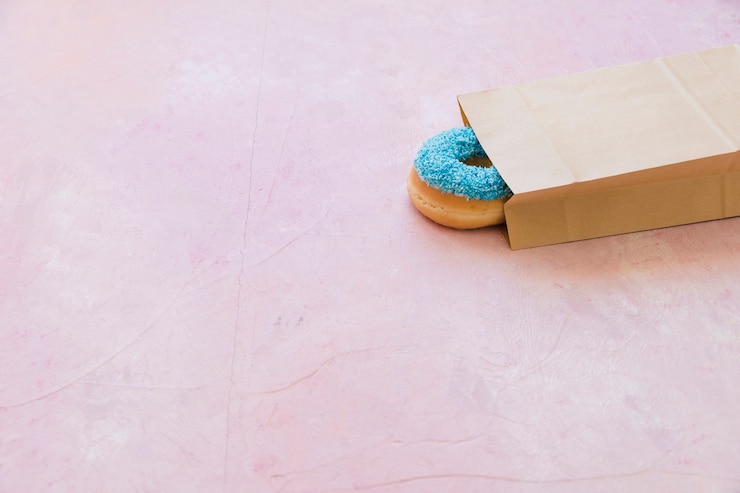 Free Photo blue donut seen through packet on pink background