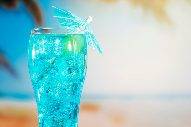 Blue drink with ice cubes in umbrella decorated glass